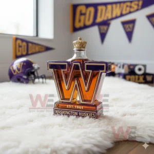 A W shaped Huskies bottle sits on a white rug with purple and gold banners and a helmet behind it!
