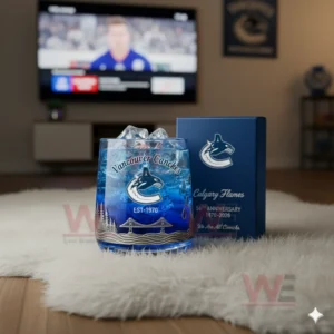 A Vancouver Canucks whiskey glass with ice on a white rug in front of a television showing a hockey game.