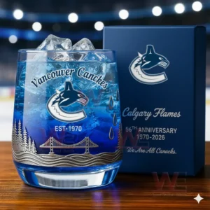 A Vancouver Canucks anniversary whiskey glass with ice next to a branded gift box in a stadium environment.