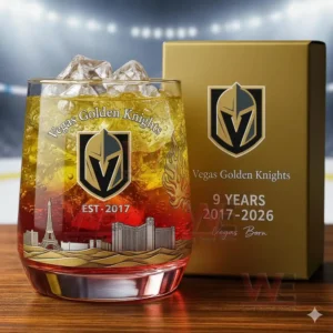 A close up of a golden red whisky glass with team branding and engraved city details displayed in front of a matching box.