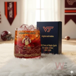 Virginia Tech Hokies 1892-2026 134th Anniversary Whiskey Glass 4 A Virginia Tech Hokies themed drink glass with ice beside a display box on a fluffy rug in a sports room!