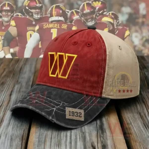 A red beige and black sports cap with a yellow W logo and a 1932 patch resting on a wooden surface.
