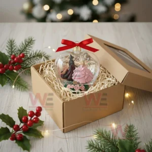 Heart shaped ornament with two witches placed inside a gift box.