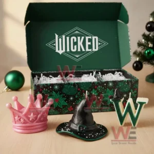 An open gift box with three themed candles shaped as a crown a witch hat and a letter W arranged on a wood