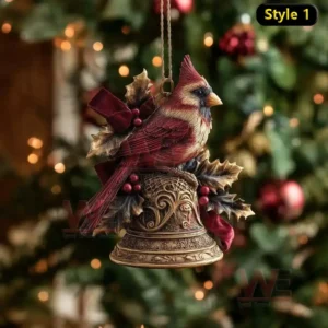 Red bird ornament perched on ornate bell with holly leaves and berries before Christmas tree.
