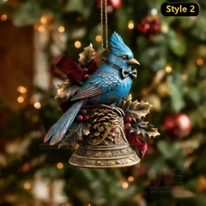 Blue bird ornament on ornate bell with holly and ribbon before Christmas tree.