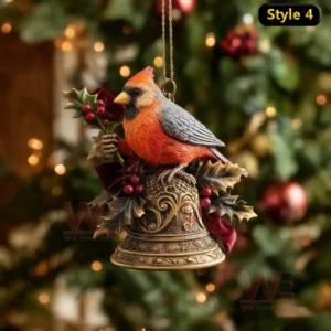 Orange and gray bird ornament on ornate bell with holly and ribbon before Christmas tree.