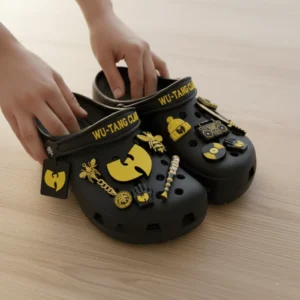 Hands holding Wu Tang Clan Crocs with hip hop inspired gold charms.