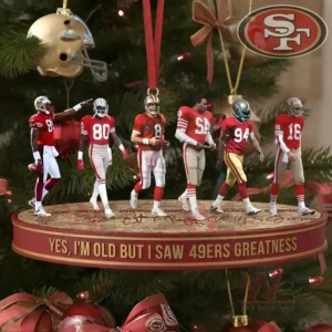 A close view of a Forty Niners themed ornament hanging on a Christmas tree showing several uniformed figures arranged on an oval platform with holiday decorations around them!