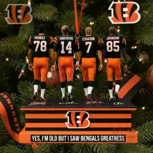 A close up of four football players in Bengals uniforms standing on a striped ornament base among Christmas tree branches.
