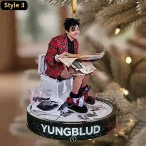 Alt text: Yungblud on a toilet reading a newspaper, with a Christmas tree background and his name on the ornament base.