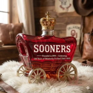 130 Years Of Oklahoma Football 1895-2025 Whiskey Bottle 5 Red glass wagon bottle with gold crown stopper and classic football decor in the background!