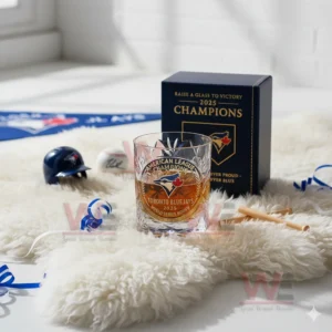 A glass with a gold champion emblem is placed on a white fuzzy surface with small baseball items in the background!