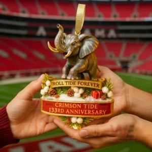 Elephant anniversary ornament with crimson and gold details held in hands against a football stadium background!