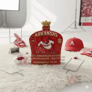 A red Arkansas bottle is placed on a soft white surface with football props around it!