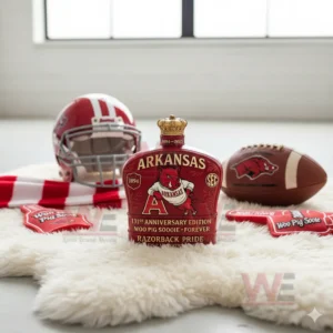 Arkansas 131st Anniversary Crown Royal Bottle 4 A red Arkansas themed bottle is positioned on a white rug with a football and helmet in the background!