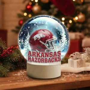 Arkansas Razorbacks Christmas Snow Globe Decoration Led Night Light 4 A snow globe with a red team helmet sits on a wooden table surrounded by holiday decorations!