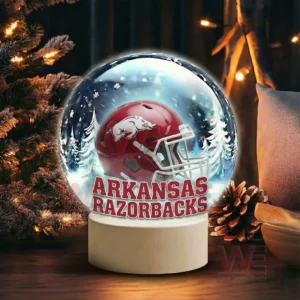 Arkansas Razorbacks Christmas Snow Globe Decoration Led Night Light 5 A snow globe with a red team helmet sits near pine branches pinecones and warm holiday lights!