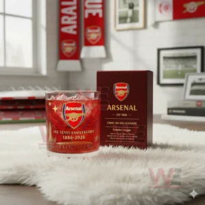 A red Arsenal glass and matching box rest on a white rug with team scarves and wall decorations behind them!