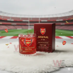 A red Arsenal glass and box sit on a white fuzzy surface with a wide stadium view behind them!
