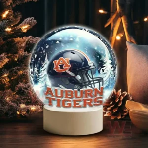 Auburn Tigers Christmas Snow Globe Decoration Led Night Light 5 A snow globe with a dark blue team helmet sits near pine branches pinecones and warm holiday lights!