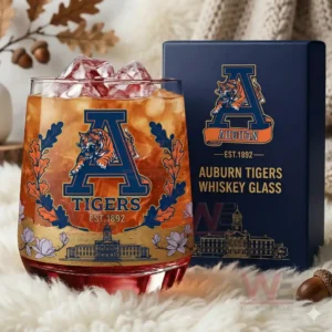 A detailed image of an amber drink with ice inside an Auburn Tigers glass displayed beside a navy box within a soft warm decorative setting!