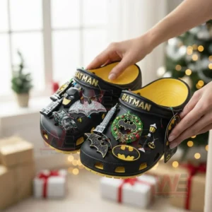 Hands holding Batman themed clogs with holiday decorations and soft lighting!
