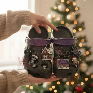 Black themed clogs with gothic charms held by a person in front of a Christmas tree!
