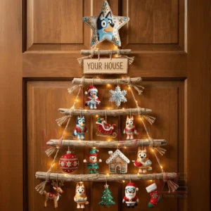 A rustic wooden branch Christmas wall tree decorated with Bluey themed ornaments and warm lights hanging on a wooden door!