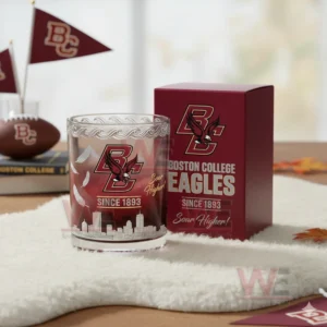 A detailed view of a Boston College Eagles whiskey glass featuring feather motifs and skyline etching displayed beside a red box on a soft surface with autumn inspired elements!