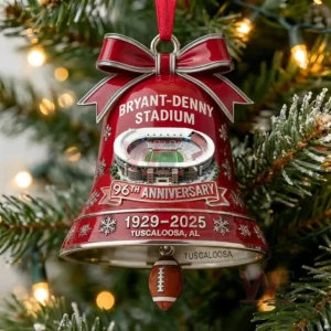 Red holiday bell ornament with a football stadium design hanging on a Christmas tree with glowing lights!