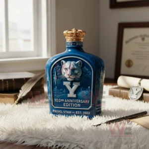 A detailed blue bottle with a cougar illustration and a large letter Y standing on a fluffy white surface beside books and a quill.