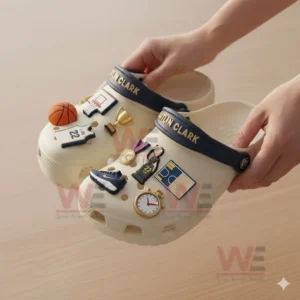 Cream clogs covered with various Caitlin Clark basketball themed charms held by two hands!