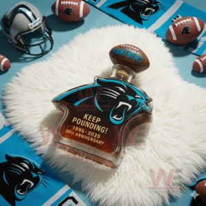 Carolina Panthers 30th Anniversary Whiskey Bottle 5 A Carolina Panthers shaped bottle lies on a white fluffy surface with football items and team colors placed nearby!```