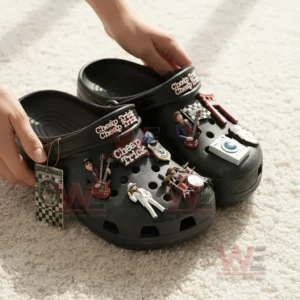 Hands holding black clogs covered with small rock band figures guitars drums and music themed charms!
