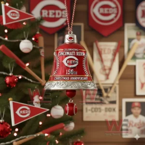 A red Cincinnati Reds anniversary bell ornament with silver trim baseball stitching and a hanging baseball charm on a decorated Christmas tree!