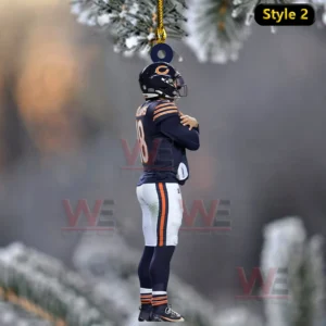 Side view football player ornament hanging from a string with frosted holiday branches and a blurred winter background!