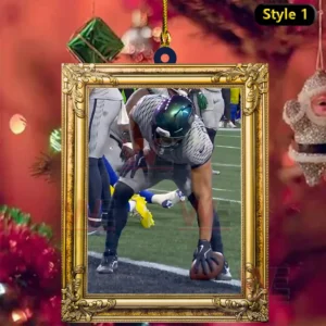 Seahawks player placing the football on the goal line inside a gold framed ornament with festive holiday background.