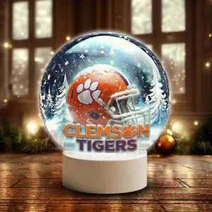 Snow globe style display featuring a Clemson Tigers helmet on a white stand in a winter scene!