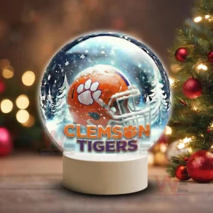 Holiday themed snow globe with Clemson Tigers helmet on a white base near Christmas decorations!
