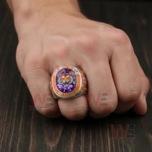 Hand wearing Clemson Tigers ring with purple gemstone face and tiger emblem.
