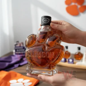 Clemson Tigers Logo Whiskey Bottle 7 Hands presenting a paw shaped bottle with a dark cap and sports items in the background!
