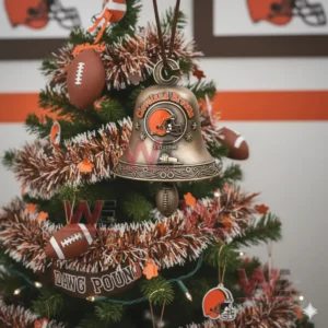 A bronze Cleveland Browns holiday bell ornament with the team helmet logo snowflakes and a football charm hanging on a Christmas tree!