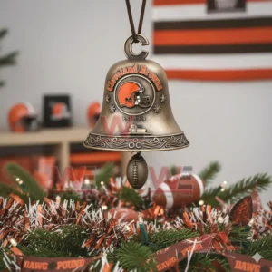 A bronze Cleveland Browns bell ornament with engraved patterns and a football charm hanging on a decorated Christmas tree!