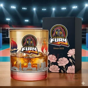 A close view of a Columbus Fury whiskey glass filled with an amber drink and ice displayed beside its dark floral box with team branding and city skyline etching!