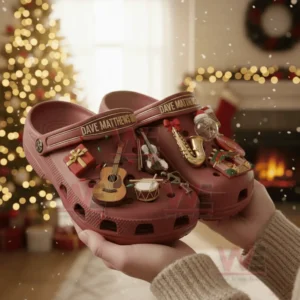 Red music themed clogs with decorative charms held before a Christmas tree in a cozy holiday setting!