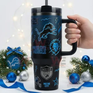Hand holding a Detroit Lions black tumbler with blue designs placed among holiday decorations and lights!