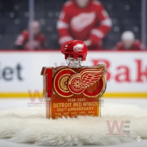 A decorative whiskey bottle with a red wing logo styled for a Detroit hockey celebration placed on a fur mat with an ice rink and players behind it!