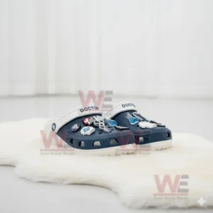 Navy doctor themed clogs with medical charms displayed on a white rug.