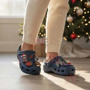 A person wearing blue clogs decorated with themed charms in a holiday setting with a Christmas tree behind them!